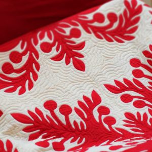 白い生地に、赤い糸で刺繍を施した、ハワイアンキルトの写真