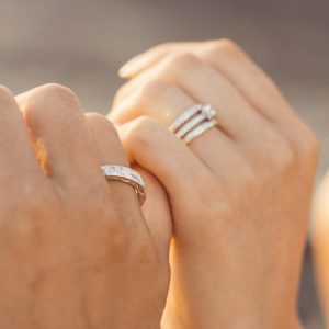 左手薬指にリング（指輪）をはめたカップルが小指を絡めている手元の写真