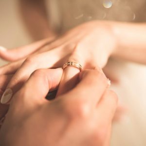 男性が女性の左手薬指に結婚指輪をはめる写真