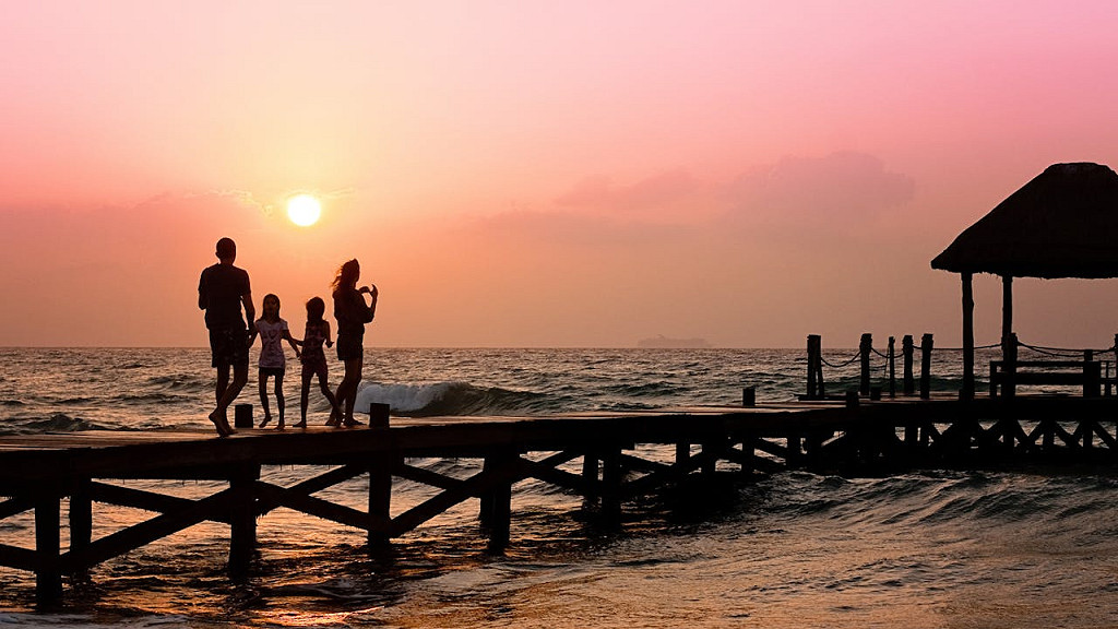 家族4人が夕暮れの桟橋で手を繋いでいる写真