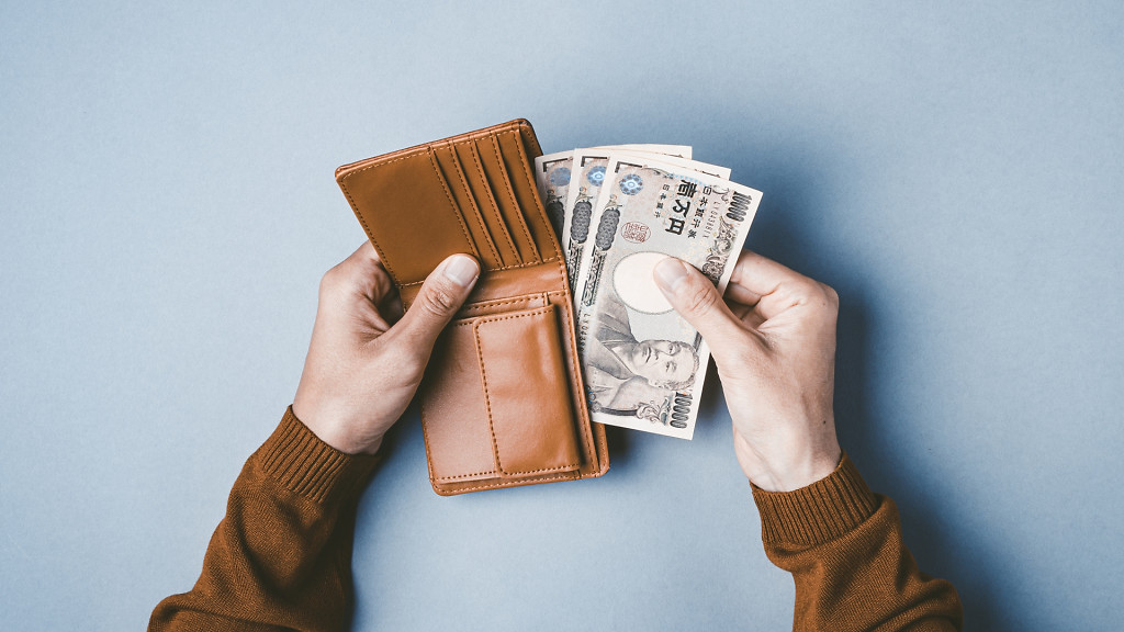 アクセサリープレゼントの予算相場をイメージした、革の財布から一万円札を取り出している手元の写真。