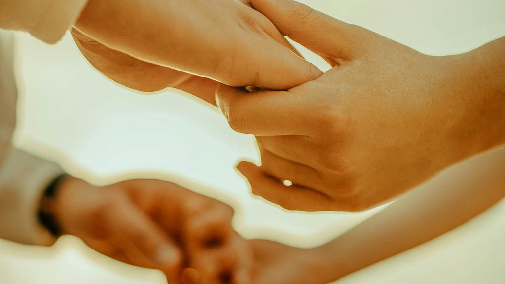 互いに手を取り合う二人の手元の写真。世代を超えて受け継がれる家族の絆と、心の資産を象徴するイメージ