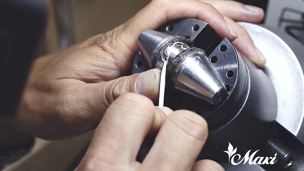 ハワイの自社工房にて、職人がシルバーリングに手作業で彫り柄を施している、Maxiの製作風景