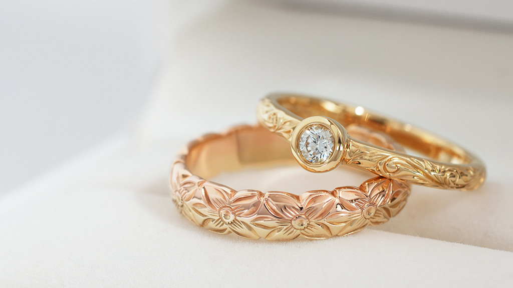 Maxiのゴールド製ハワイアンジュエリー。プルメリア柄のリングと、一粒ダイヤモンドをあしらった婚約指輪のペア写真