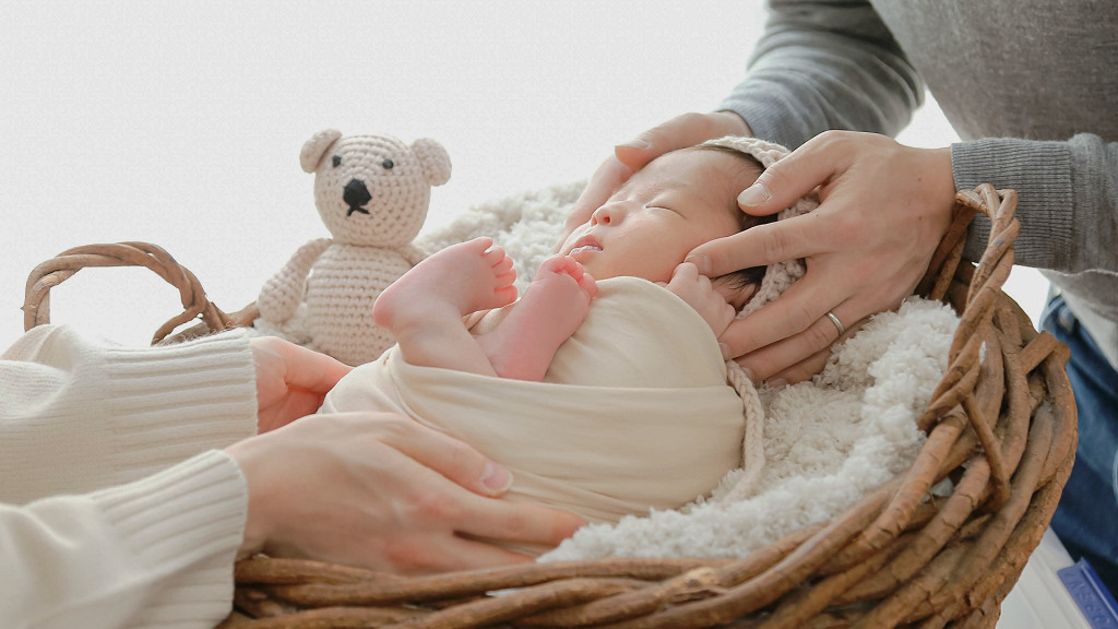 赤ちゃんがおくるみに包まれ、ニューボーンフォトの撮影の準備をしている写真